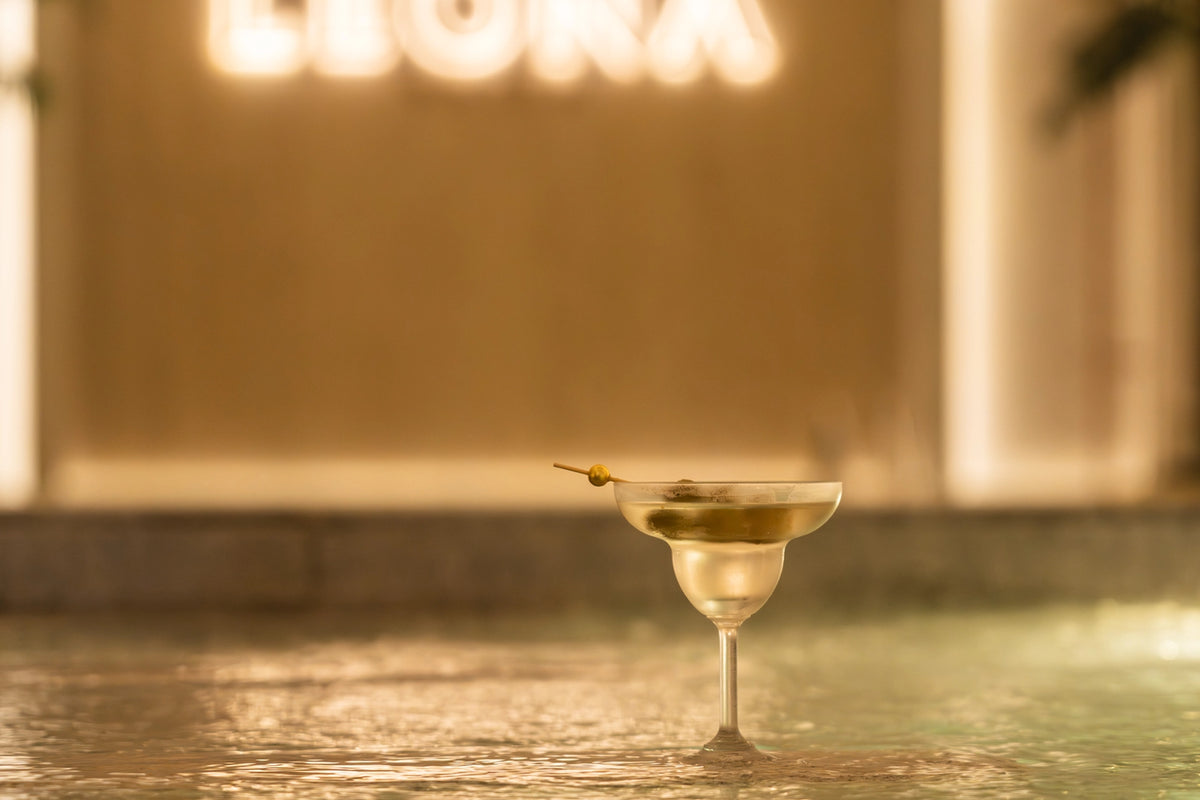 Cocktail in a martini glass with a olive in an onsen pool at Leona Onsen.